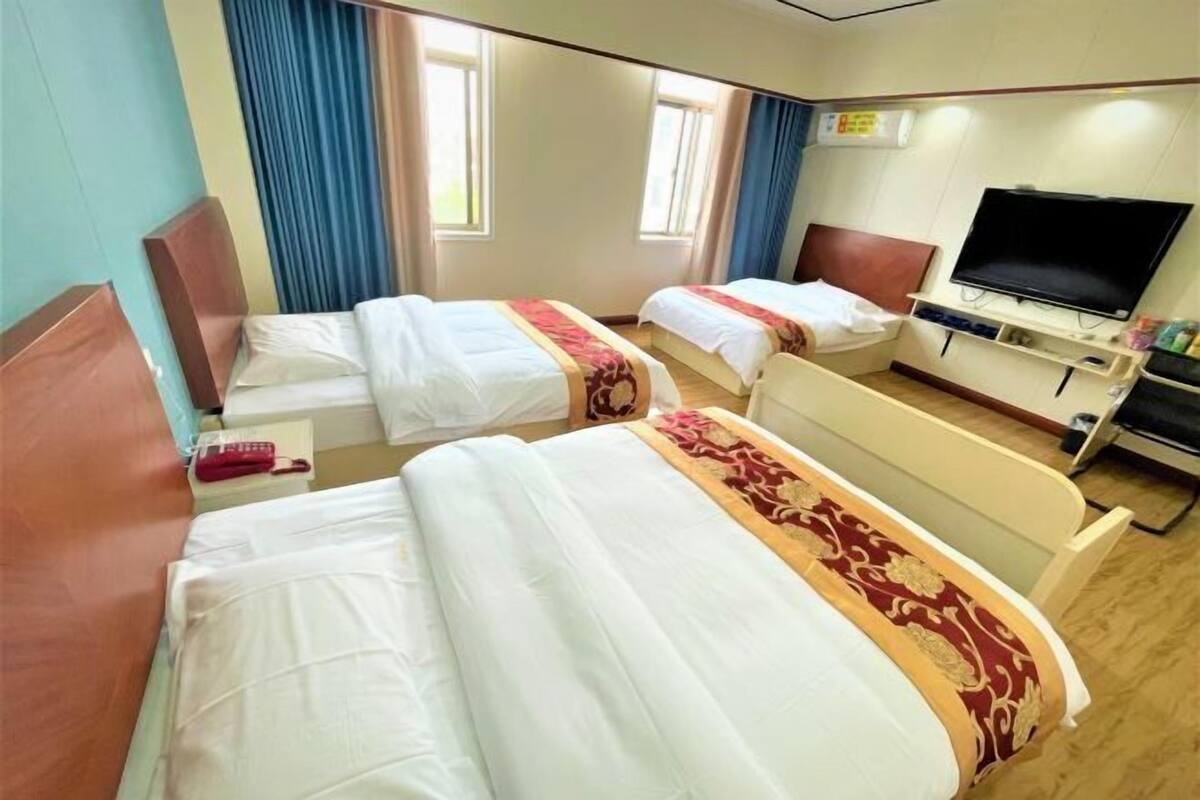 A hotel room with two beds, a TV, and a small desk.