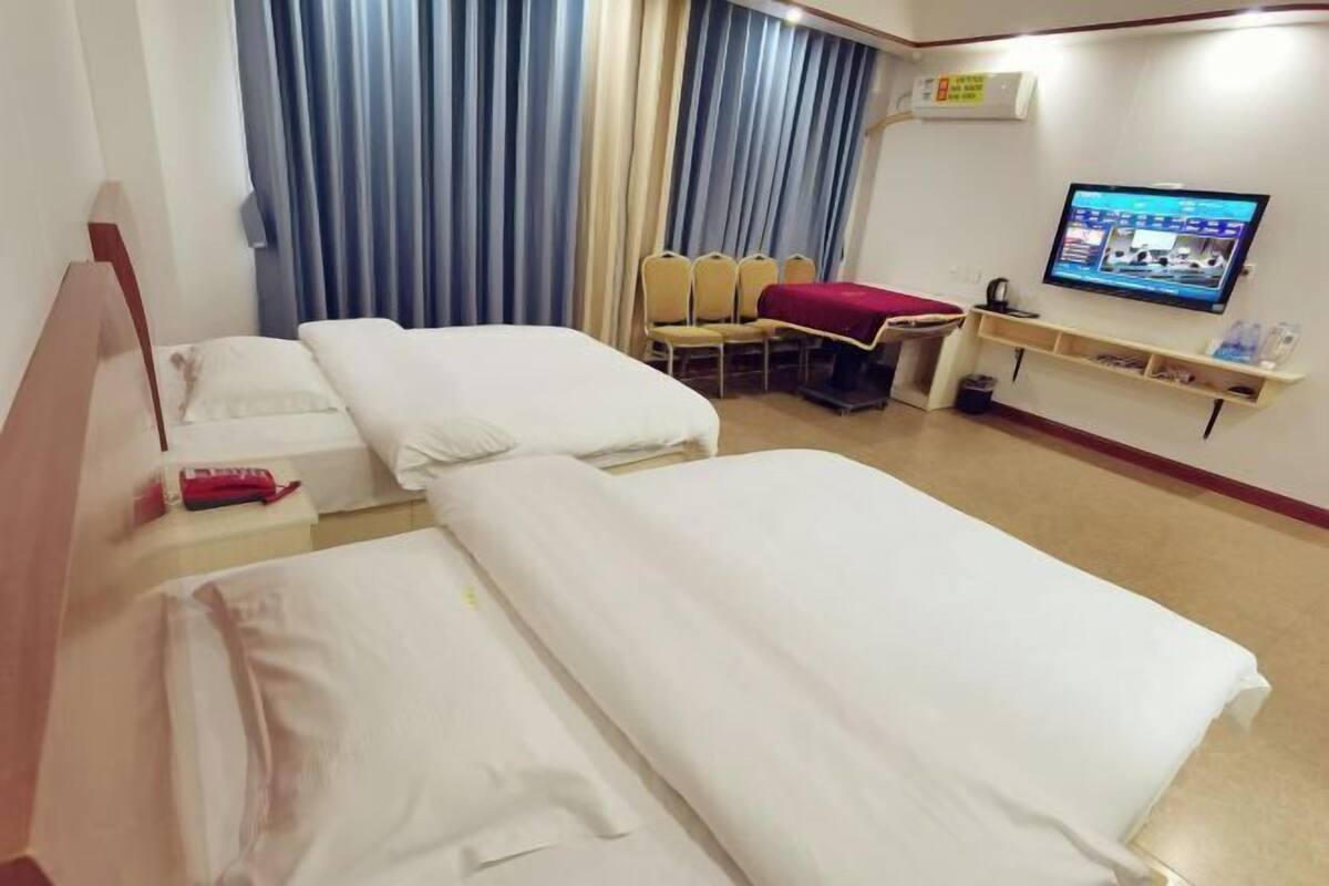 A hotel room with two beds, a TV, a desk, and a chair.