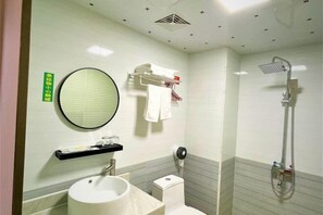 Un bany amb un mirall rodó, un lavabo, una tassa i una dutxera.
