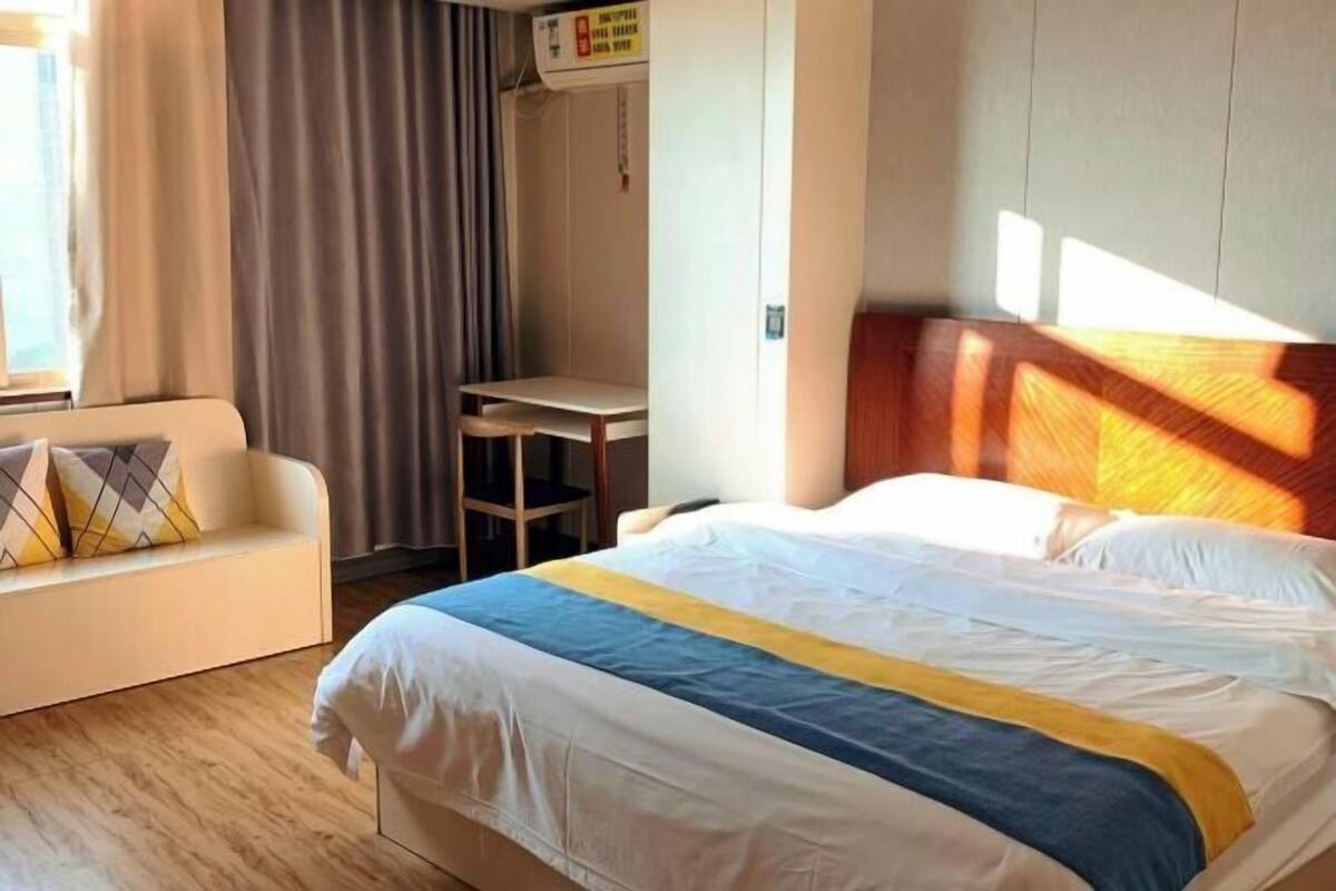 A hotel room with a bed, a sofa, a desk, and a wardrobe.