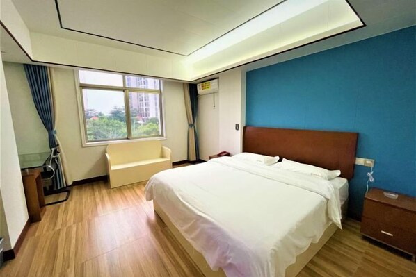 A hotel room with a bed, a window, a chair, and a wooden floor. - Wanli Hotel (Qinzhou)