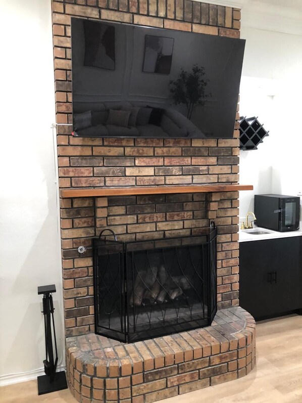A fireplace with a TV mounted above it, a black screen, and a brick surround.