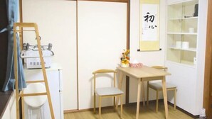 A room with a wooden table, two chairs, a small white stool, a ladder, a white cabinet, and a shelf with items. - Kokoro no sato・Ren (Kyoto)