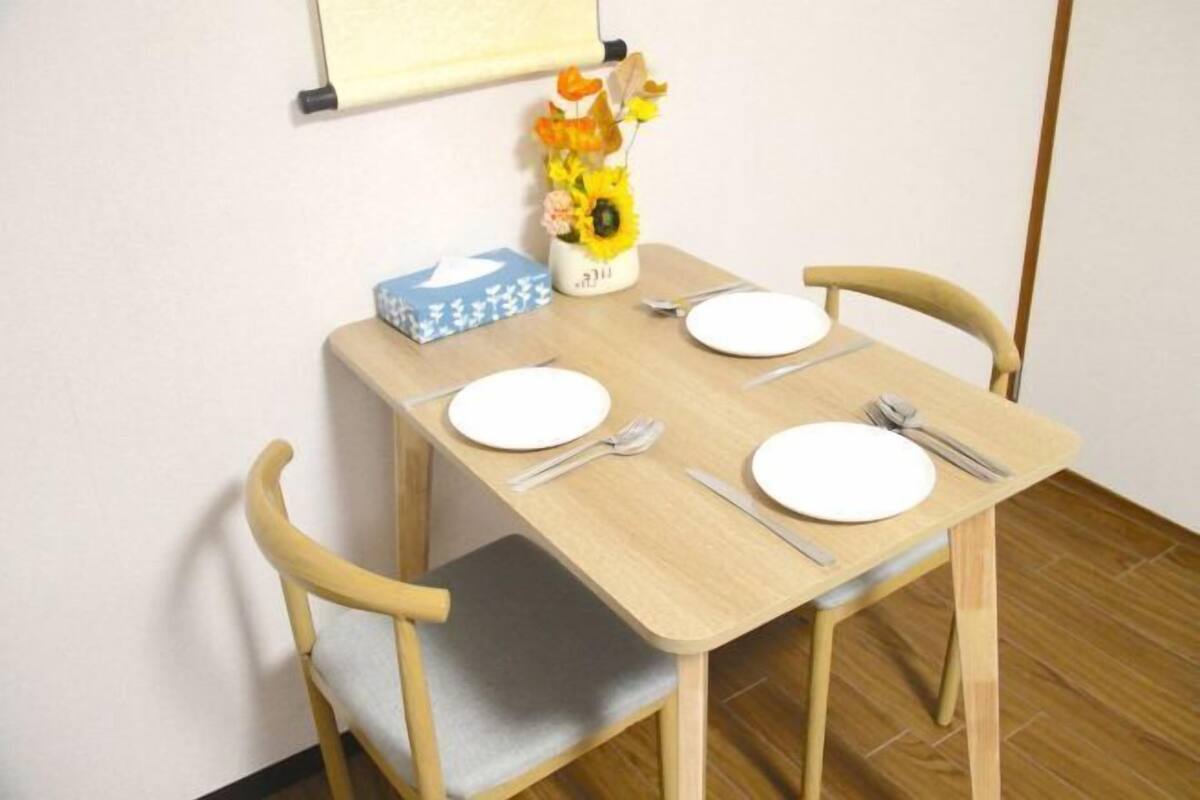 Une petite table à manger avec deux chaises, un vase avec des fleurs et une boîte posée sur la table.