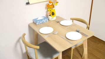 A small dining table with two chairs, a vase with flowers, and a box on the table.