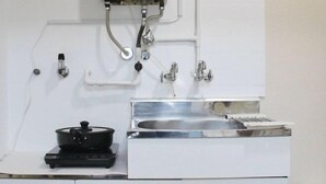 A kitchen with a stove, sink, and various pipes and valves. - Kokoro no sato・Ren (Kyoto)