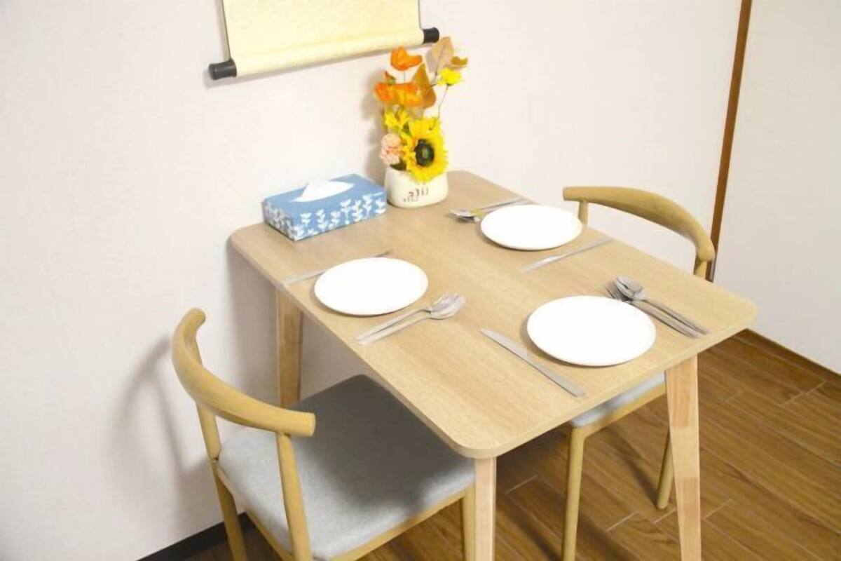 Une petite table à manger avec quatre chaises, un vase rempli de fleurs et une boîte bleue posée sur la table.
