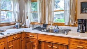 Una cocina con armarios de madera, un lavamanos y una cafetera.