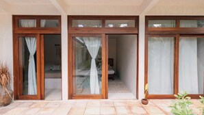 A hotel room with a sliding glass door entrance, a small balcony with a potted plant, and a view of the interior. - Villa Sanah 11 con alberca privada ubicada en Tulum (Tulum)