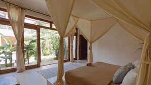 A bedroom with a large bed, curtains, and a view of greenery outside. - Villa Sanah 11 con alberca privada ubicada en Tulum (Tulum)