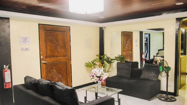 A lobby with a reception desk, a black sofa, a glass coffee table, and a potted plant. - Reddoorz @ Gabz K Travellers Inn Sorsogon City (Sorsogon City)