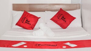 A neatly made bed with two red pillows and a white towel, a red towel on the bed, and a red bedspread with the Red Doorz logo. - Reddoorz @ Gabz K Travellers Inn Sorsogon City (Sorsogon City)