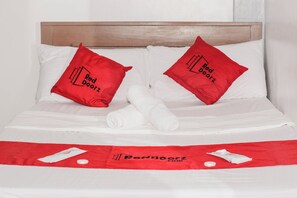 A neatly made bed with two red pillows and a white towel, a red towel on the bed, and a red bedspread with the Red Doorz logo. - Reddoorz @ Gabz K Travellers Inn Sorsogon City (Sorsogon City)