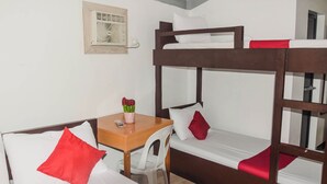 A bunk bed room with a wooden desk and chair, a small table with a vase of flowers, and a wall-mounted air conditioning unit. - Reddoorz @ Gabz K Travellers Inn Sorsogon City (Sorsogon City)