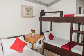 A bunk bed room with a wooden desk and chair, a small table with a vase of flowers, and a wall-mounted air conditioning unit. - Reddoorz @ Gabz K Travellers Inn Sorsogon City (Sorsogon City)