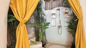 A bathroom with a shower, a small sink, and a toilet. There are yellow curtains and plants around the room. - Villa Sanah 12 con alberca privada ubicada en Tulum (Tulum)