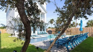 Ein Garten mit Swimmingpool, blauen Liegestühlen und einem Holzzaun.