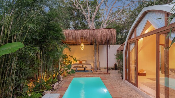 A modern outdoor pool area with a thatched roof structure, surrounded by lush greenery and a clear blue pool. - Villa Sanah 4 con alberca privada ubicada en Tulum (Tulum)