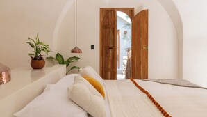 A bedroom with a bed, pillows, a hanging light, a wooden door, and a plant. - Villa Sanah 8 con alberca privada ubicada en Tulum (Tulum)