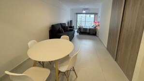 A modern living room with a white round table and chairs, a black sofa, and a bed with a patterned bedspread. - Splendid, Modern, and Cozy With Pool (Buenos Aires)