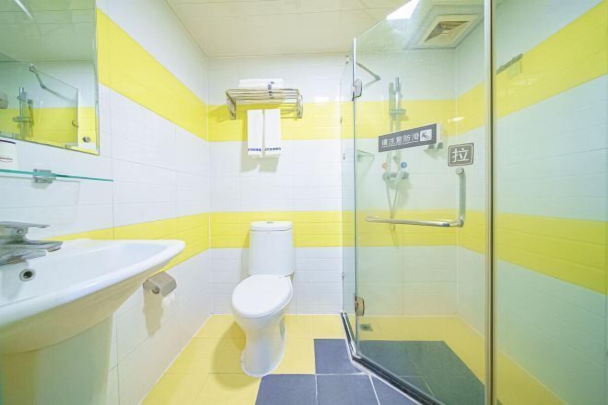 A bathroom with a glass shower enclosure, a white sink, and a toilet.