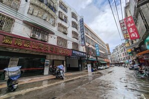 Ένας δρόμος με καταστήματα και ένα κτίριο με πολλούς ορόφους και μπαλκόνια.