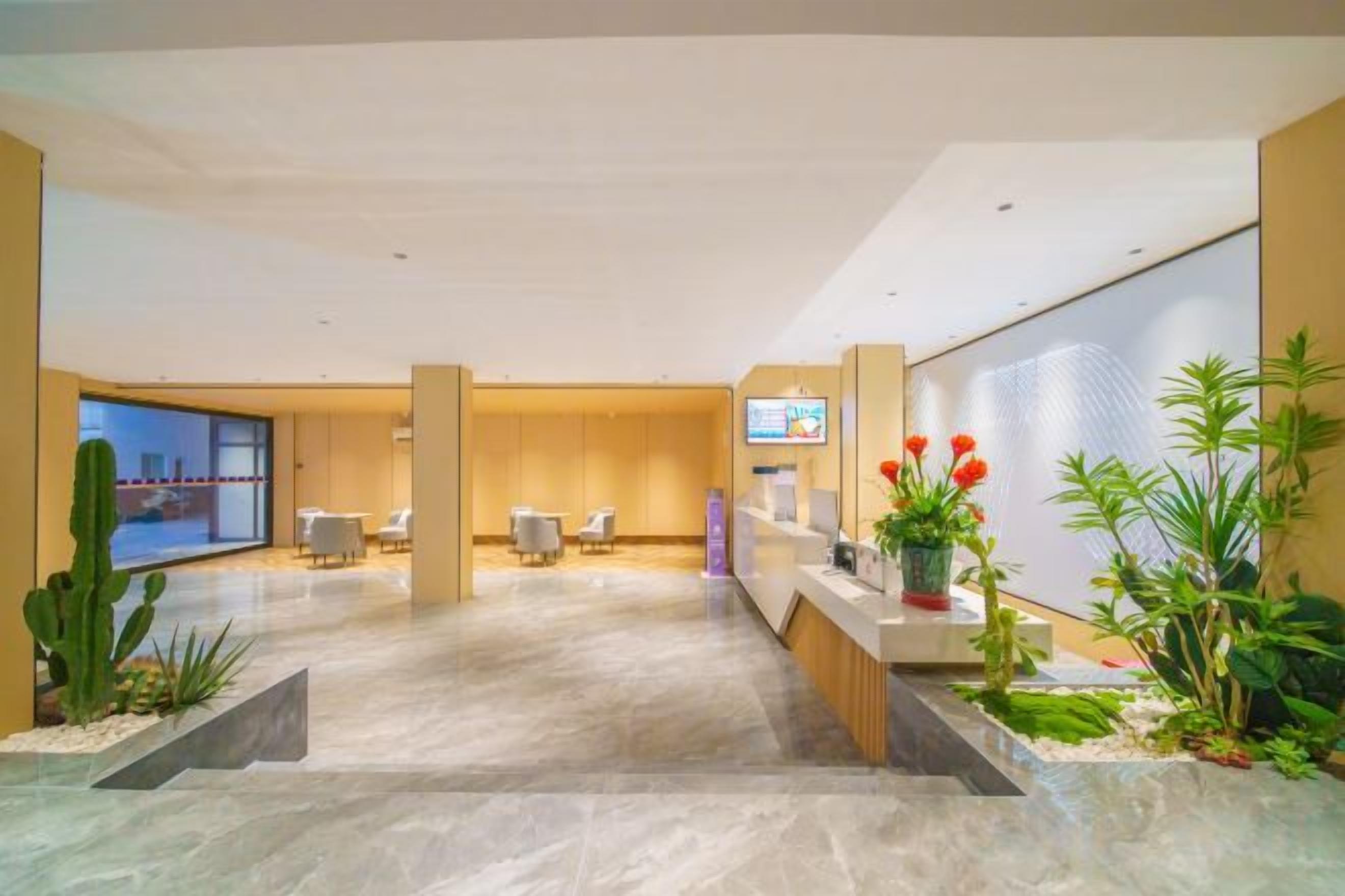 Un vestíbulo de hotel con mostrador de recepción, zona de estar y un amplio ventanal.
