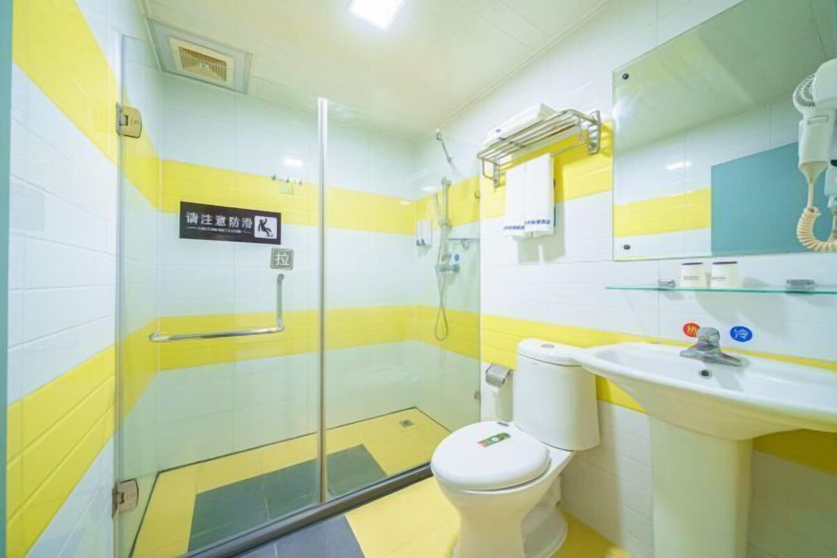 A bathroom with a glass shower enclosure, a white toilet, and a sink with a mirror above it.
