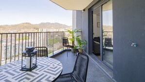 A balcony with a round table and chairs, a potted plant, and a view of a cityscape and mountains. - Cubo's Urban Sky Apartment Malaga View 17 / urban / air conditioning / free wifi / community pool (Málaga)