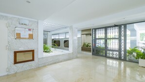 Un hall d’entrée spacieux avec un sol en marbre, un comptoir de réception et une cloison décorative en verre.