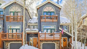 Une cabane en rondins à deux étages, avec des fondations en pierre, des balcons en bois et une entrée en pierre.