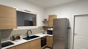 A modern kitchen with wooden cabinets, a stainless steel refrigerator, a microwave, and a sink. - "Tenuta Lu Beddhru" Oasis of peace in Salento a stone's throw from the sea  (Carpignano Salentino)