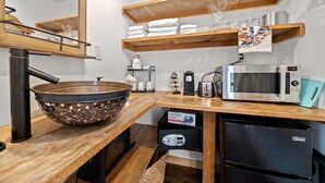 Une cuisine avec un plan de travail en bois, un grand saladier, un four à micro-ondes, une machine à café et un réfrigérateur.