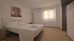 A bedroom with a bed, a nightstand, a window, and a door. - Hotel Key Reig (Almussafes)