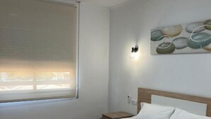 A neatly made bed with white linens and towels, a wooden headboard, a nightstand with a lamp, and a painting on the wall. - Hotel Key Reig (Almussafes)