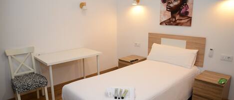 A neatly arranged hotel room with a bed, a desk, a chair, and a nightstand.