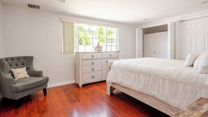 Een slaapkamer met een bed, een kaptafel, een stoel en een raam met gordijnen.