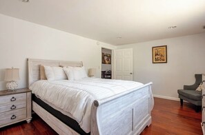 Une chambre à coucher avec un grand lit, une table de chevet, une chaise et une porte.