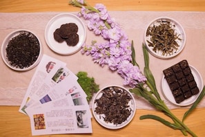 A table with various items including bowls of dried herbs, a chocolate bar, and a bouquet of flowers. - Xizhengjia Apartment (Guangzhou Pazhou Exhibition Wanshengwei Subway Station Branch) (Guangzhou)