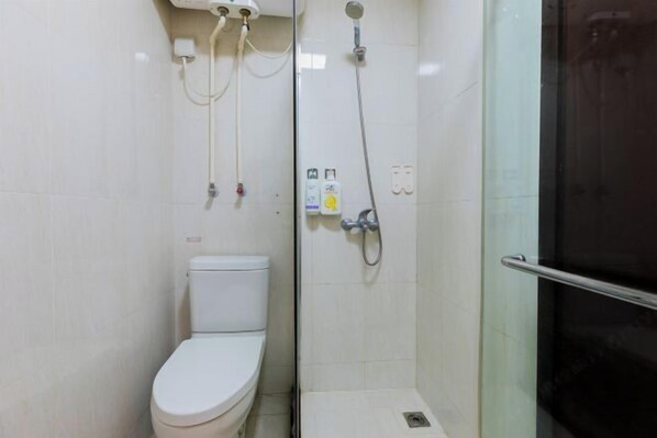 A bathroom with a toilet, a shower with a glass door, and a handrail. - Xizhengjia Apartment (Guangzhou Pazhou Exhibition Wanshengwei Subway Station Branch) (Guangzhou)