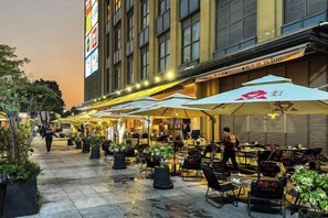 An outdoor café with tables and chairs, umbrellas, and potted plants. - Xizhengjia Apartment (Guangzhou Pazhou Exhibition Wanshengwei Subway Station Branch) (Guangzhou)