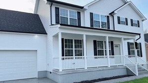 A two-story house with a garage, a covered porch, and a staircase leading to the entrance.