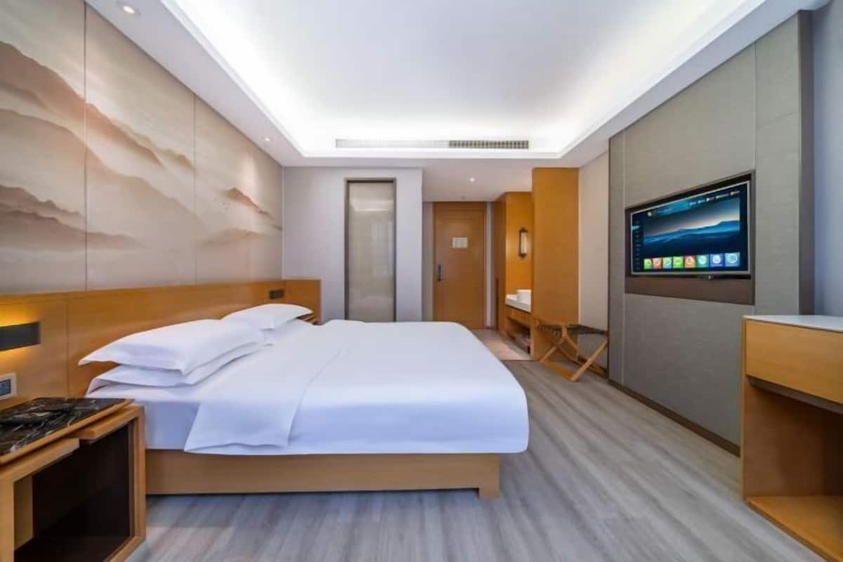 Una habitación de hotel moderna con una cama, un televisor, un escritorio y una obra de arte en la pared.