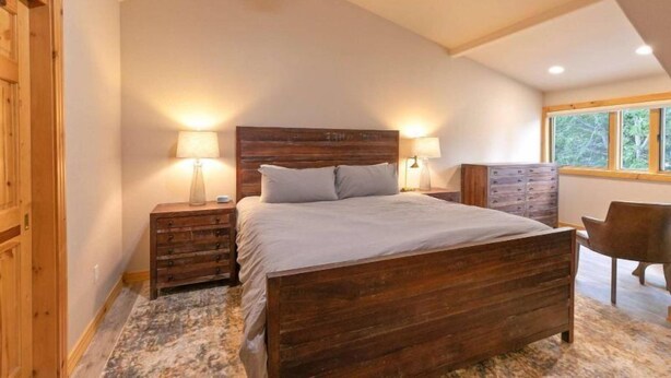 A bedroom with a wooden bed, nightstands, a dresser, and a window with a view of trees. - 5 Bedroom Luxury Townhome Near Snowflake Lift in Breckenridge - Walk to Lift! (Breckenridge)