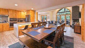 A modern kitchen with wooden cabinets, a central island, and a dining area with a large table and chairs. - 5 Bedroom Luxury Townhome Near Snowflake Lift in Breckenridge - Walk to Lift! (Breckenridge)