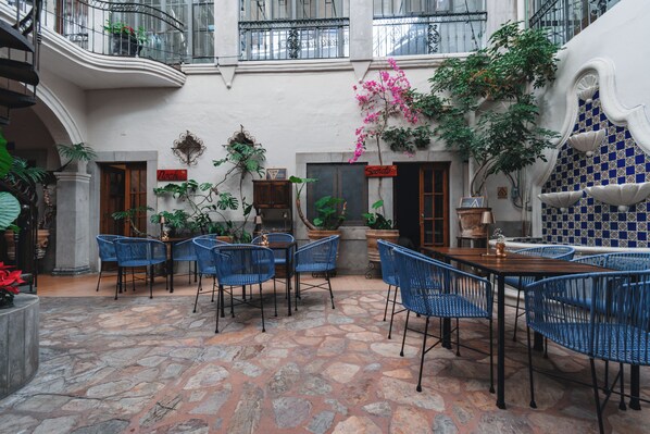 Une cour avec un sol en pierre, des chaises bleues et des plantes en pot.