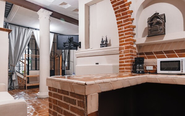 A kitchen with a brick oven, a microwave, and a coffee maker. - Te Amo Hotel Boutique (San Miguel de Allende)