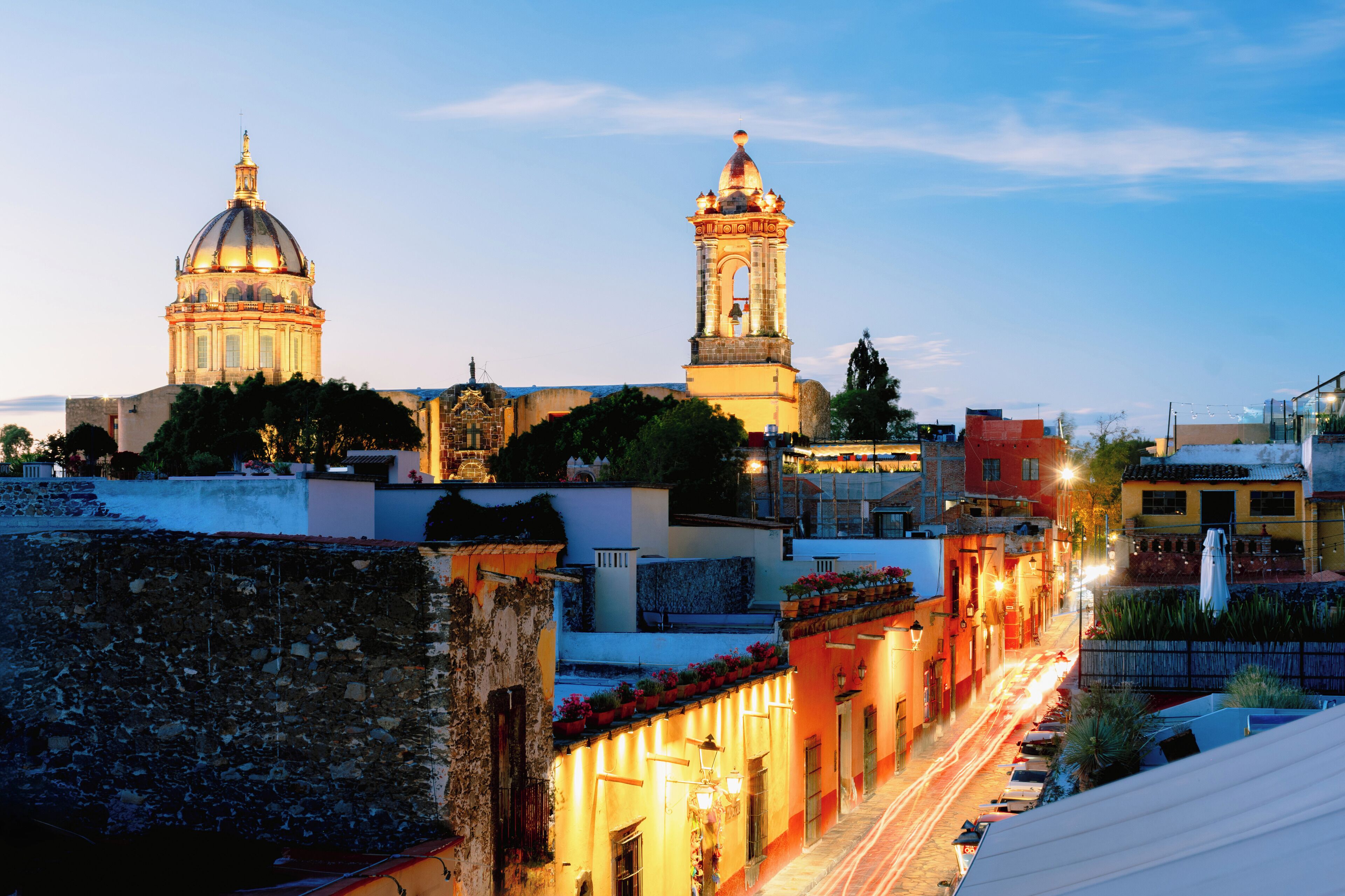 Una calle histórica con edificios, una cúpula de iglesia destacada y un campanario.