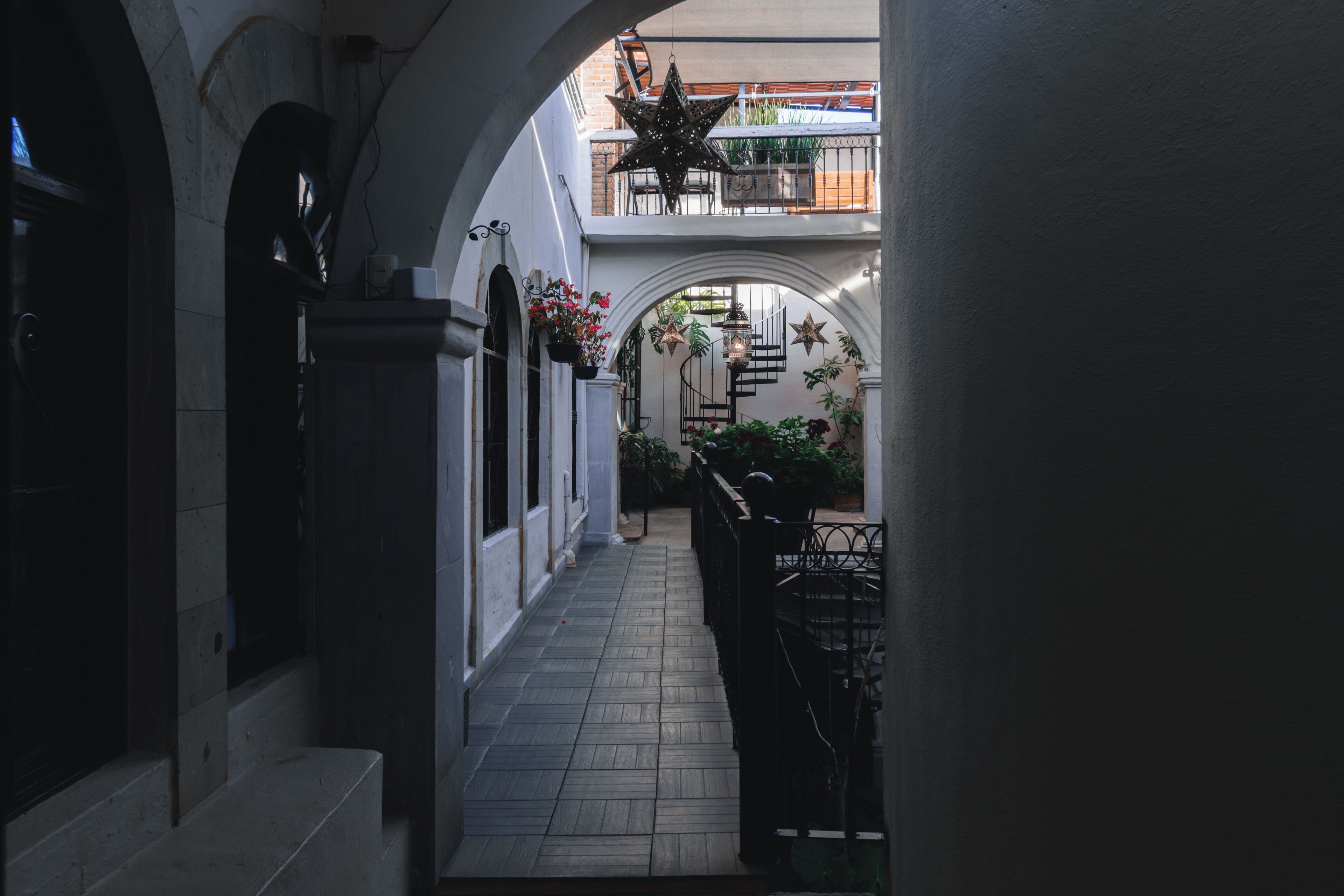 A narrow corridor with tiled flooring, white walls, and a small staircase leading to an upper level.