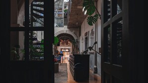 Een binnencorridor met betegelde vloer, een trap en uitzicht op een balkon met planten.